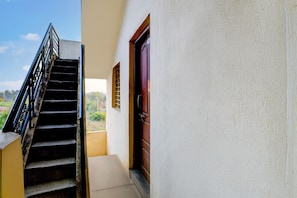 A staircase leading to a door with a window, a white wall, and a clear sky.