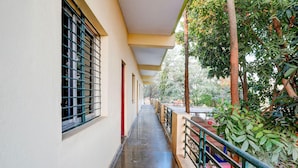 Passadís amb una galeria coberta, finestres amb reixes de metall i una barana amb vista a un jardí.