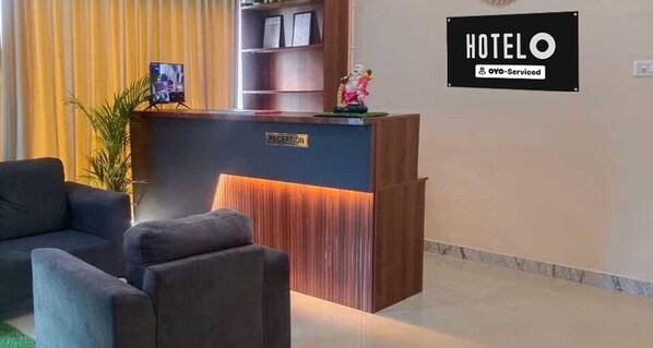 Una mesa de recepción de hotel con un letrero que dice 'RECEPTION', un cuadro enmarcado y una pequeña estatua encima.