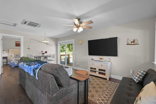 A modern living room with a sofa, a television, and a dining area with a table and chairs. - Pumpkintown Mountain View Cottage (Pickens)