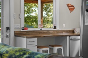 A kitchen with a wooden countertop, a sink, a window with a view of trees, and a small stool. - Pumpkintown Mountain View Cottage (Pickens)