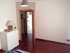 A room with a wooden floor, a white dresser, a lamp, and a door leading to another room. - LA BELLA Flat, Super Easy Venice, Bus stop right in front of Venice (short ride) (Venezia)