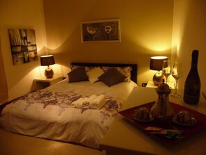 A hotel room with a bed, bedside lamps, a nightstand, a tray with a bottle, glasses, and a decorative item. - LA BELLA Flat, Super Easy Venice, Bus stop right in front of Venice (short ride) (Venezia)