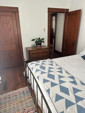 Un dormitorio con cama, cómoda, planta en maceta y espejo.