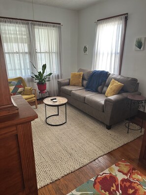 En stue med sofa, sofabord og en potteplante.