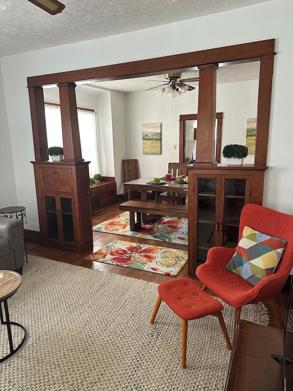 Un comedor con una mesa y sillas de madera, una alfombra y un armario con puertas de cristal.