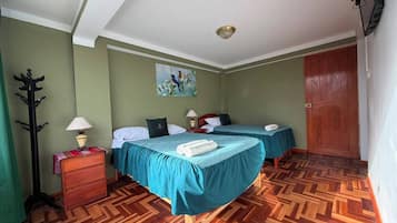 A hotel room with two beds, a wooden floor, a painting on the wall, and a door.