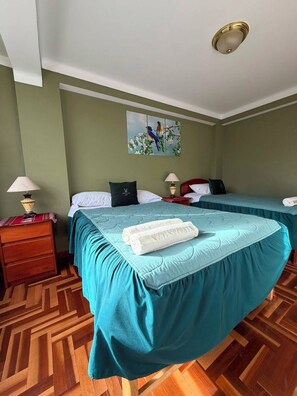 A hotel room with two beds, a painting on the wall, and a patterned wooden floor. - Rituales Inn San Borja  (Cusco)