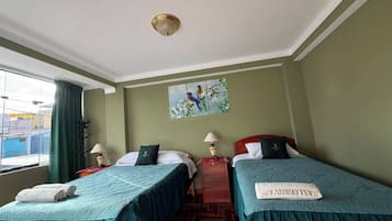 A hotel room with two beds, a window with curtains, a painting on the wall, and a ceiling light.