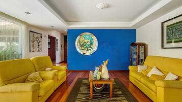 Una sala de estar con dos sofás amarillos, una mesita de centro y una pared azul destacada.