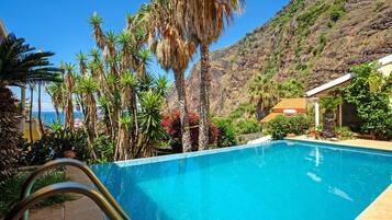 Una piscina con vistas a un paisaje montañoso y un edificio de techo rojo.