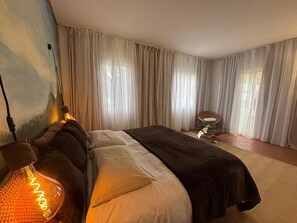 Une chambre à coucher avec un lit, des rideaux, une chaise et une lampe.
