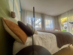 Une chambre avec deux lits, une lampe et une fenêtre avec des rideaux.