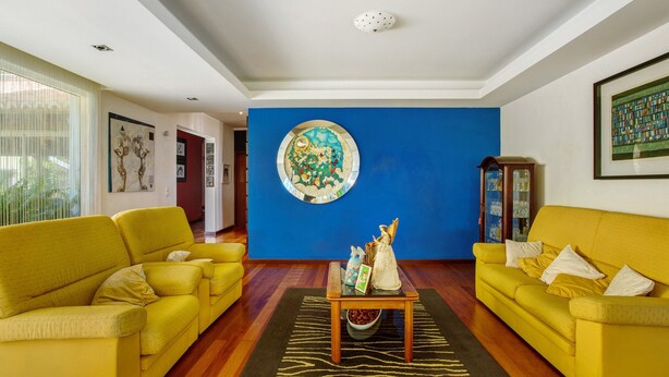 A living room with two yellow sofas, a coffee table, and a blue accent wall. - Room 'Suite Vigia Jardim' with Sea View, Wi-Fi and Air Conditioning (Jardim do Mar)