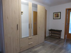 A room with a wooden wardrobe, a bench, and a framed picture on the wall. - NEW! The Eisenhower Family Nest (Aurich)