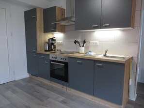 A modern kitchen with grey cabinets, a built-in oven, and a wooden countertop. - NEW! Eisenhower's Cozy Nest (Aurich)