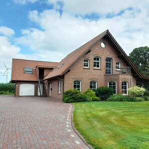 A two-story brick building with a sloped roof, a garage, and a well-maintained lawn. - NEW! Eisenhower's Cozy Nest (Aurich)