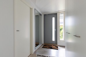 A hallway with a sliding glass door leading to a room, a door with a window, and a doormat on the floor.