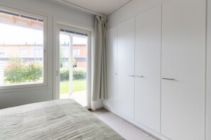 A bedroom with a bed, a wardrobe, and a sliding glass door leading to a balcony. - Casa Painter - 4BR terraced house with sauna near airport (Vantaa)