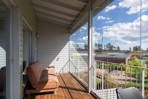 Ein Balkon mit Holzboden, einem braunen Sofa und einem Metallgeländer.