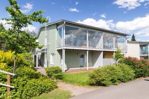 A two-story residential building with a balcony, a visible garage door, and a well-maintained garden. - Casa Painter - 4BR terraced house with sauna near airport (Vantaa)