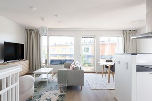 A modern living room with a flat-screen TV, a sofa, a coffee table, and a dining area with a table and chairs. - Casa Painter - 4BR terraced house with sauna near airport (Vantaa)