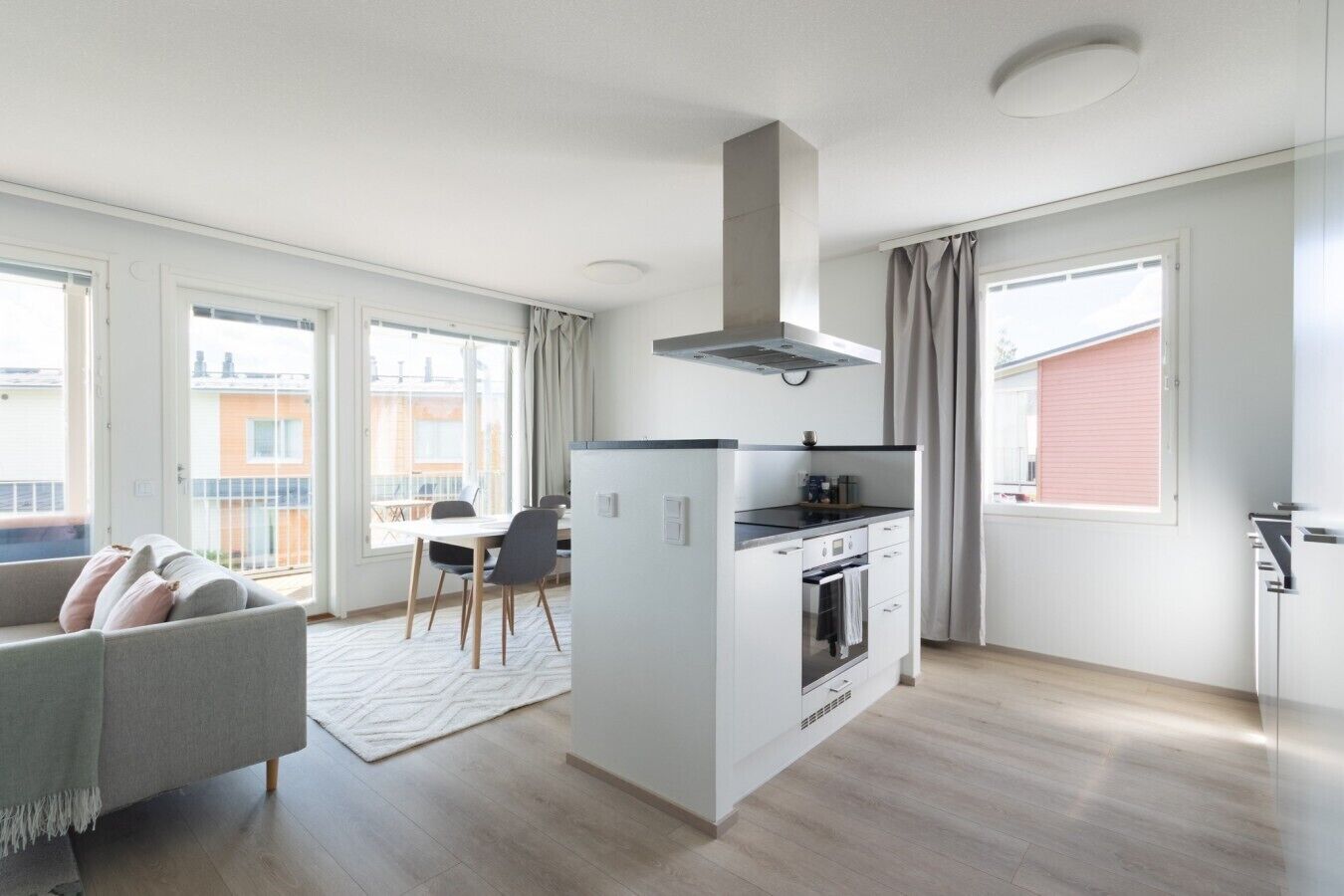 A modern apartment with a kitchenette, dining area, and a sofa.