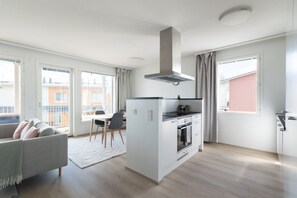A modern apartment with a kitchenette, dining area, and a sofa. - Casa Painter - 4BR terraced house with sauna near airport (Vantaa)