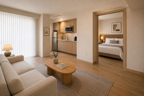 Ein modernes Hotelzimmer mit einer Couch, einem Couchtisch, einem Bett und einer Küchenzeile.
