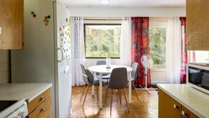 Una cocina compacta con comedor, refrigerador, microondas y ventana con cortinas.