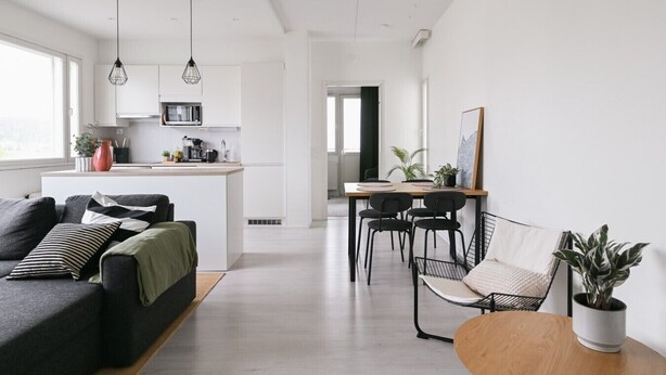 Um espaço de estar moderno com sofá, mesa de jantar, cadeiras e cozinha.