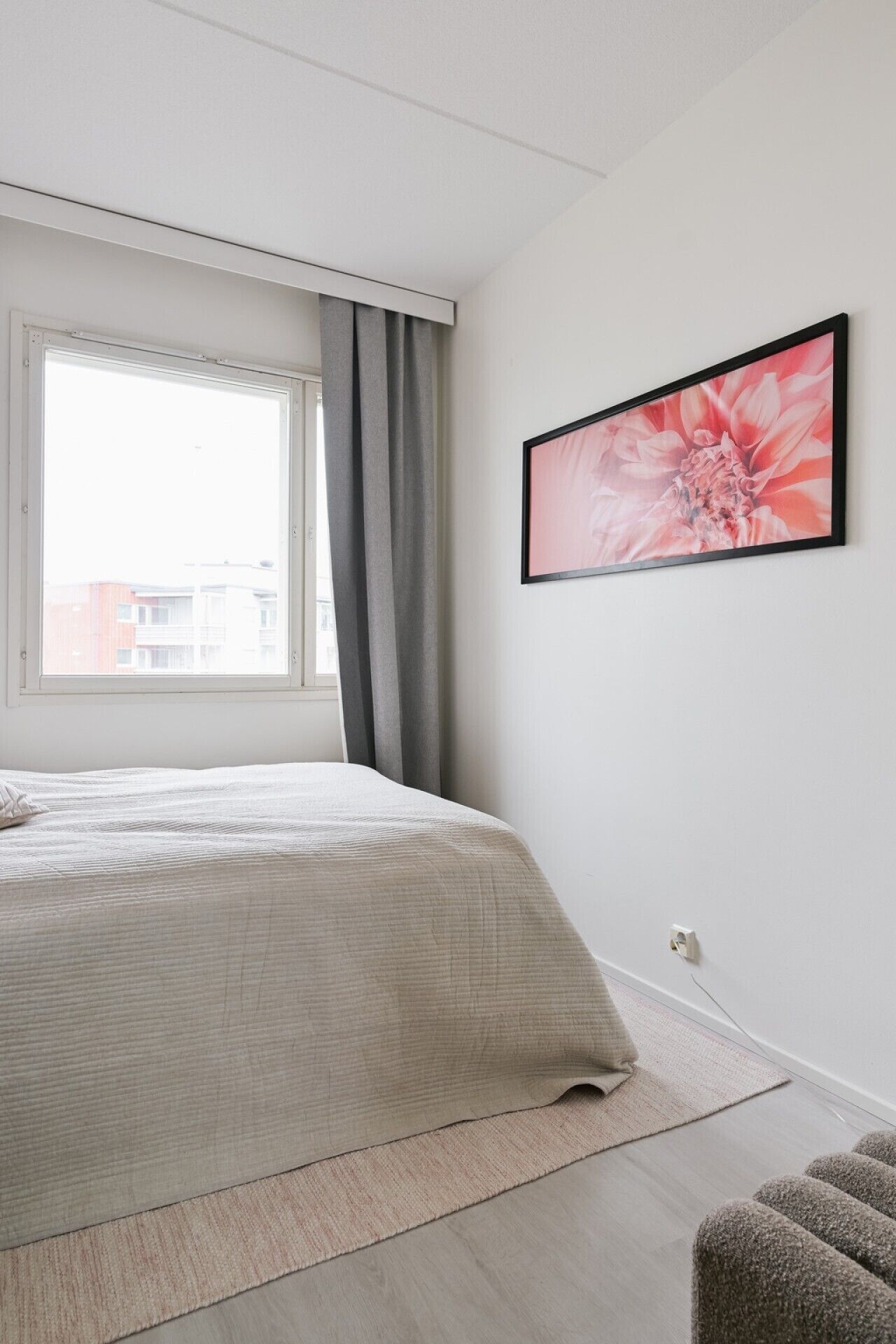 Una camera da letto con un letto, una finestra con tende, un quadro appeso al muro e un pavimento rivestito di moquette.