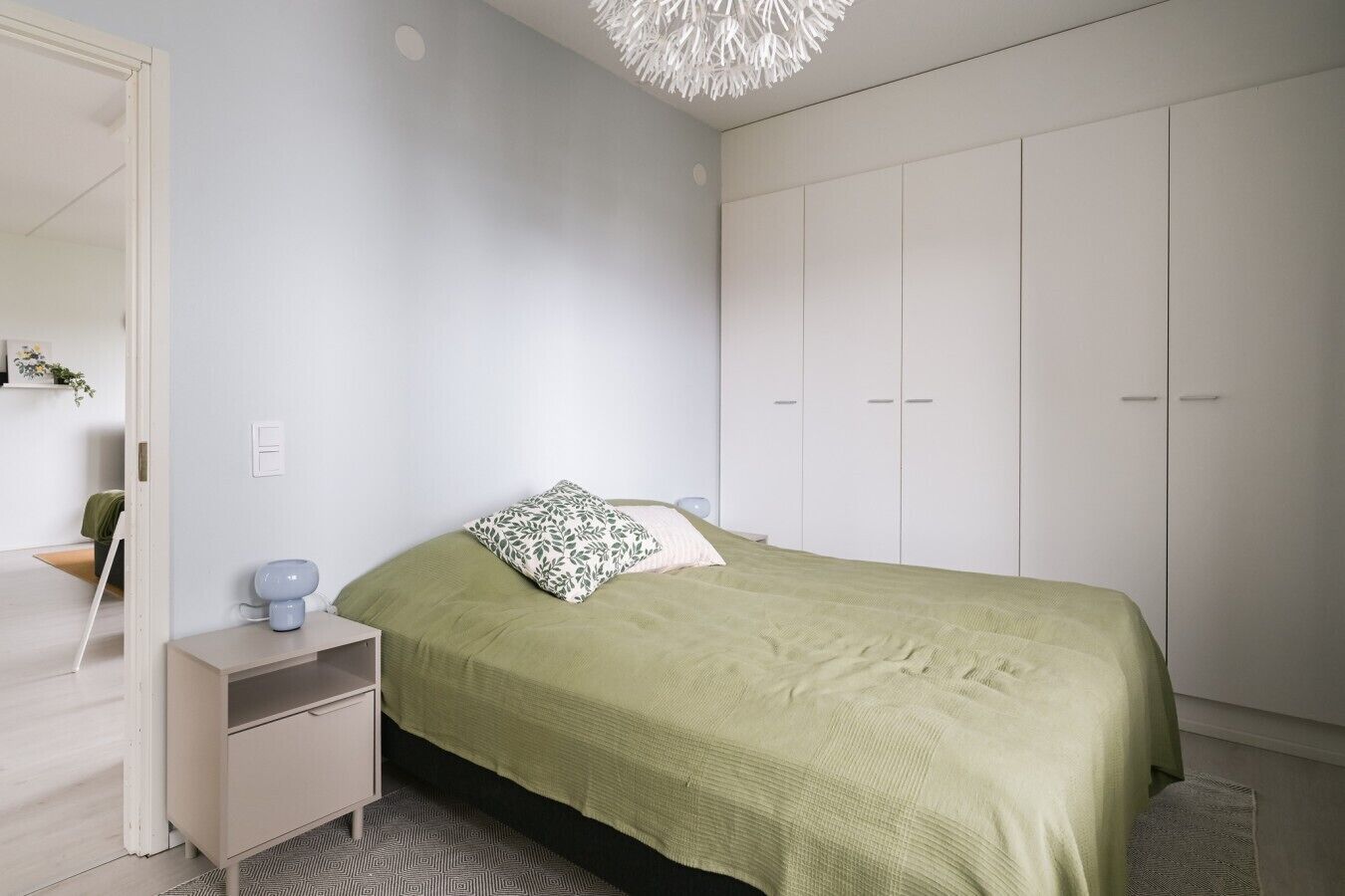 Ein Schlafzimmer mit Bett, Nachttisch, Kleiderschrank und einer Pendelleuchte.