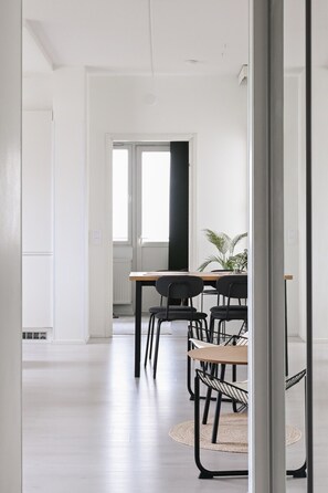 A modern interior with a dining area featuring a table and chairs, a radiator, and a large window. - Casa Lutakko - Lakeview 2BR with Balcony (Jyväskylä)