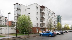 Um edifício residencial com vários andares, varandas, um estacionamento e um poste de luz.