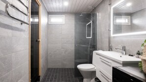 Casa de banho moderna com chuveiro, sanita e lavatório.
