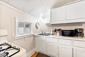 A kitchen with white cabinets, a stainless steel sink, a microwave, and a coffee maker. - Peaceful 3-bedroom house with AC in charming Fredonia (Fredonia)