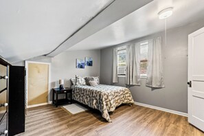 A bedroom with a bed, nightstand, lamp, and artwork on the wall. - Peaceful 3-bedroom house with AC in charming Fredonia (Fredonia)