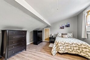 Un dormitorio con cama, cómoda, mesita de noche y una puerta.