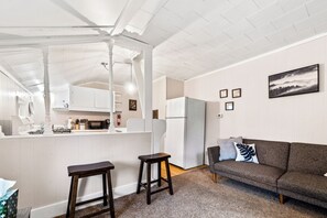 Un espacio habitable compacto con kitchenette, un sofá y una zona de comedor.