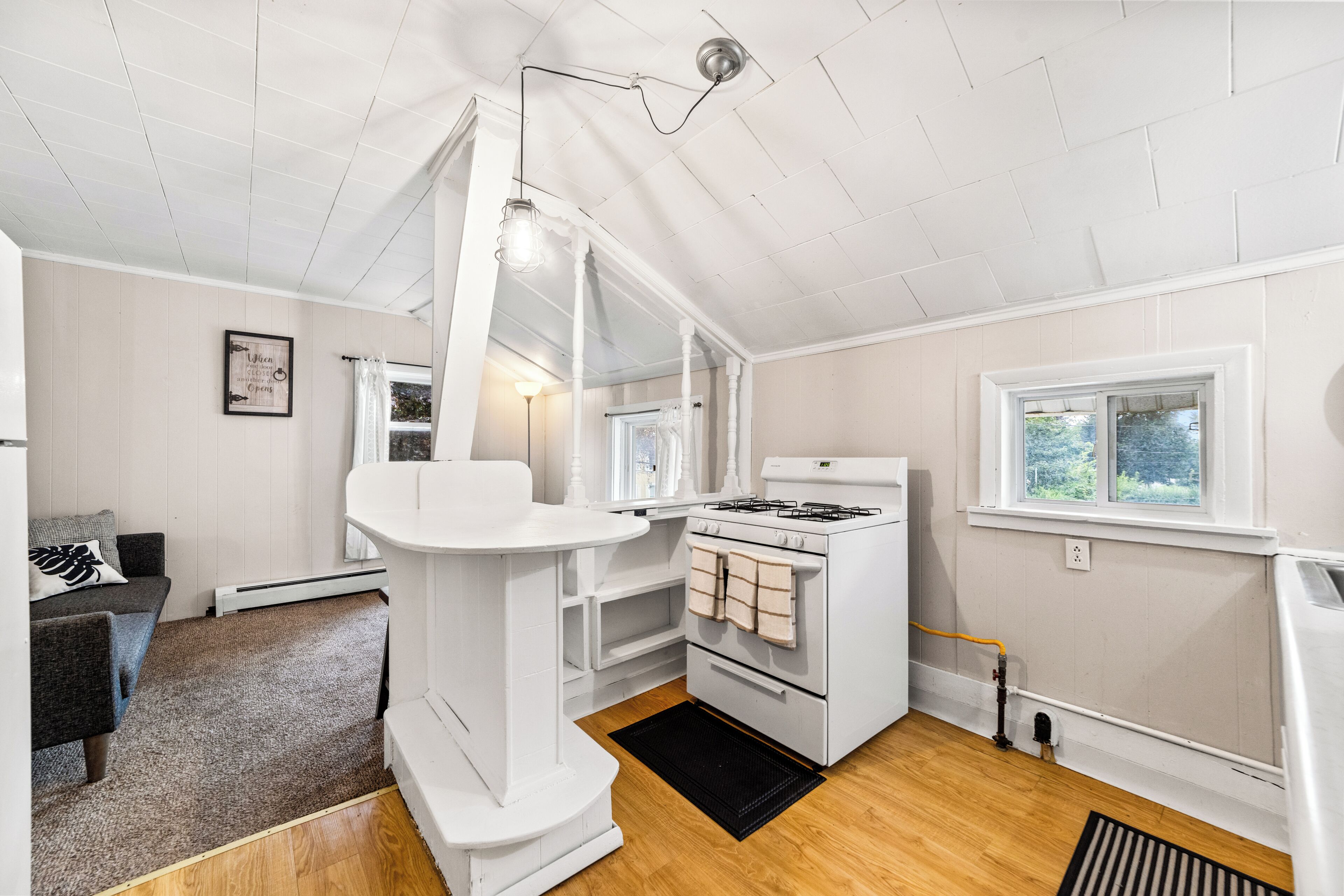 A compact kitchen with a white stove, oven, and a hanging light fixture.