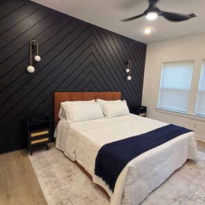 Una camera da letto con un letto, un comodino, una lampada a parete e una ventola a soffitto.