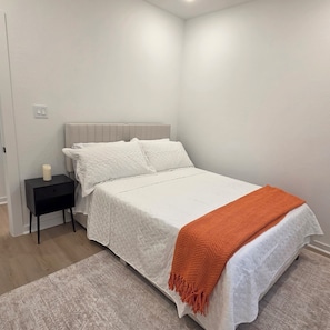 A bedroom with a bed, a nightstand, and a bedside table. - Houston Oasis / Near Downtown• NRG • Med Ctr (Houston)