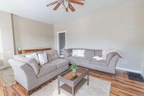 Ein Wohnzimmer mit Ecksofa, Couchtisch und Deckenventilator.