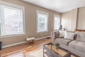 A living room with a sofa, a bench, a coffee table, and a potted plant. - Bright Mount Washington 3BR with Deck and Foosball (Pittsburgh)
