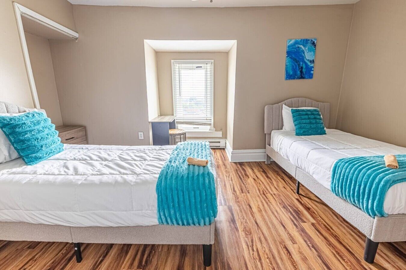 A bedroom with two beds, a desk, and a window.