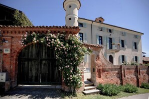 A traditional building with a large arched entrance, a brick wall, and a tower. - Historic villa in the Monferrato villages (Montiglio Monferrato)