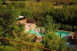 Ein Poolbereich mit Holzdeck und einem kleinen Gebäude, umgeben von üppigem Grün.