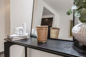 Ein Spiegel, der einen Raum mit einem schwarzen Tisch, einer Glasvase und einer weißen Vase zeigt.