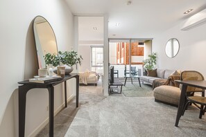 Ein modernes Wohnzimmer mit einer Couch, einem Esstisch und einem Couchtisch. An der Wand hängt ein großer Spiegel und auf dem Tisch steht eine Zimmerpflanze.